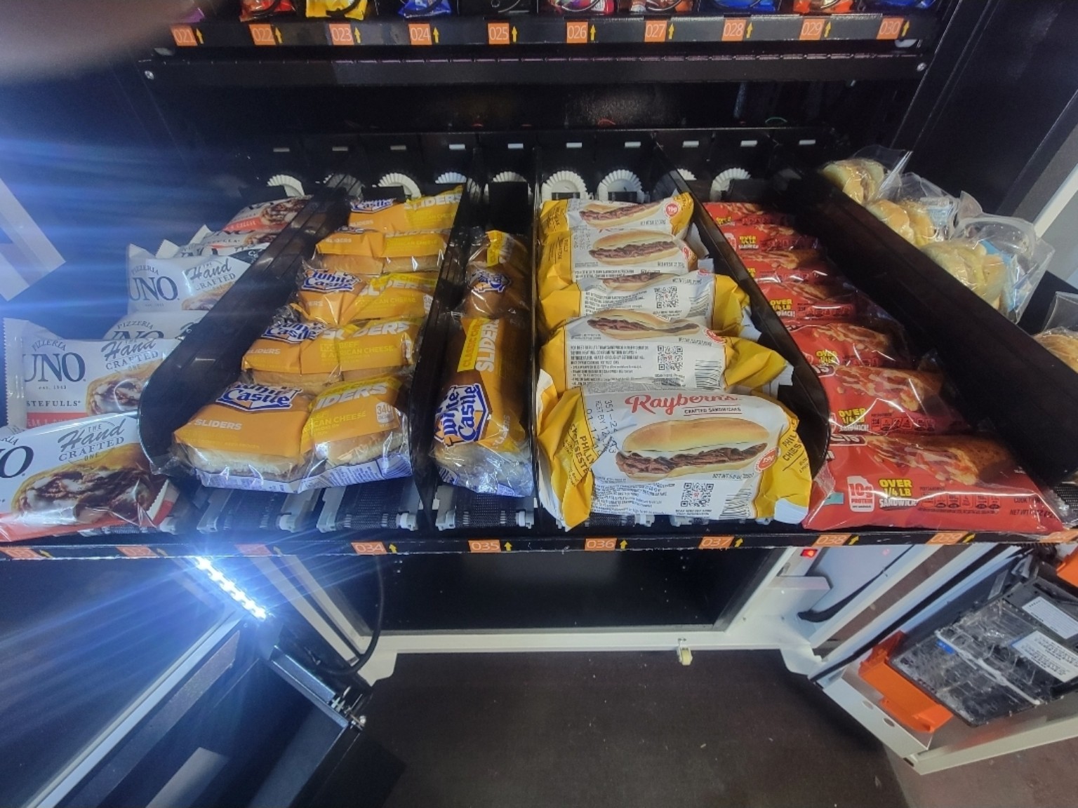 Vending conveyor rows stocked with sandwiches, sliders and meal options